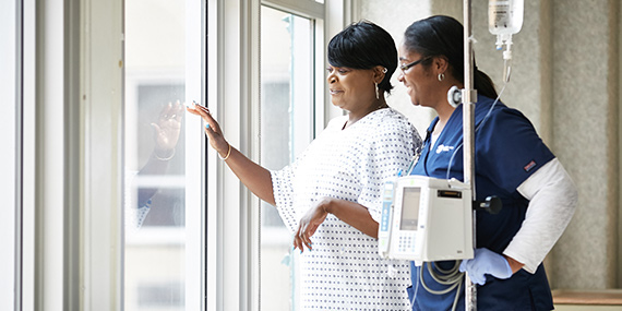 A nurse assists a patient with an IV machine