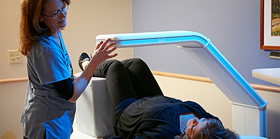 Nurse performing a bone density (DXA) scan on older woman