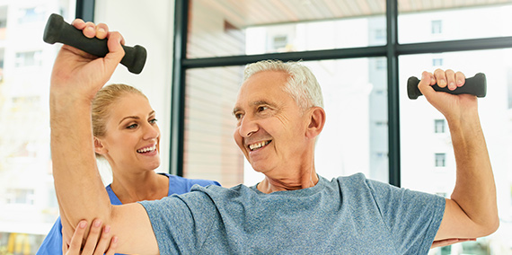 A nurse helping an older man with strengthening exercises