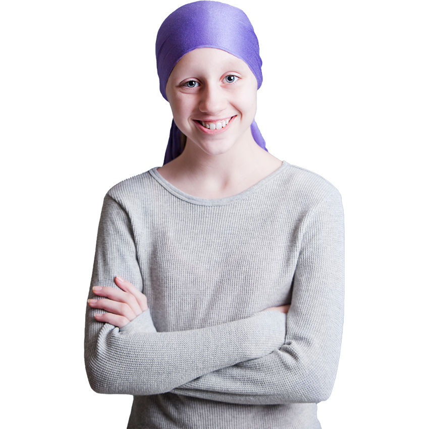 A teenage girl wearing a wrap on her head stands with her arms crossed smiling