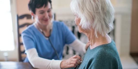 Doctor using stethoscope on old woman