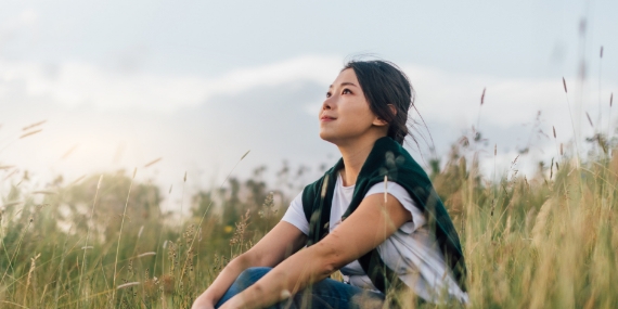 Young woman enjoying nature sitting In meadow