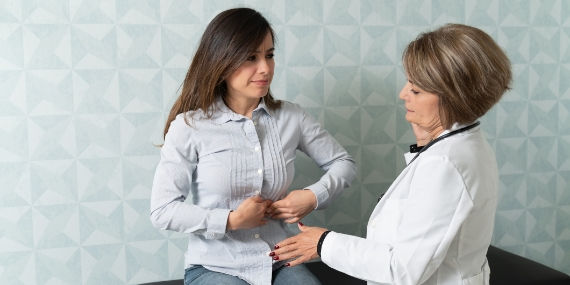 Una mujer en una cita médica que se queja de dolor de estómago
