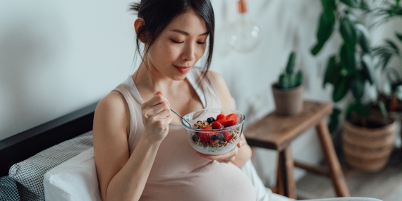 Una mujer sentada que come frutas en un tazón