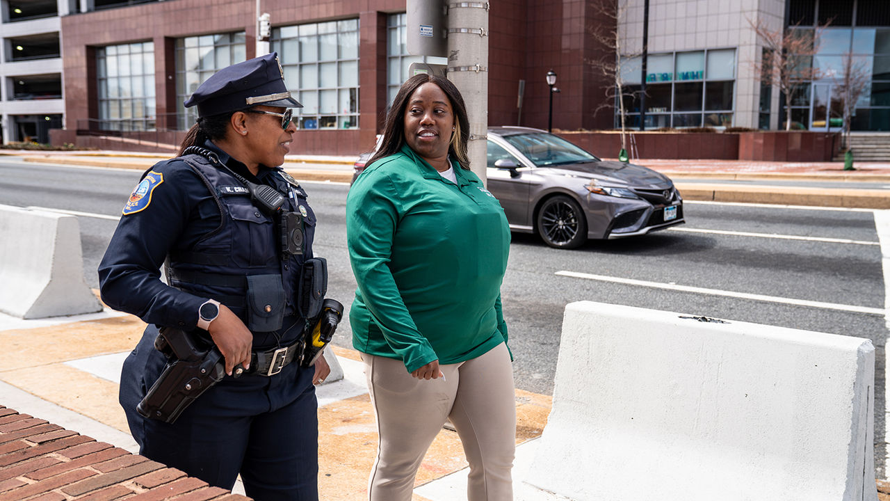A ChristianaCare community health worker walks a street in Wilmington with a uniformed police officer