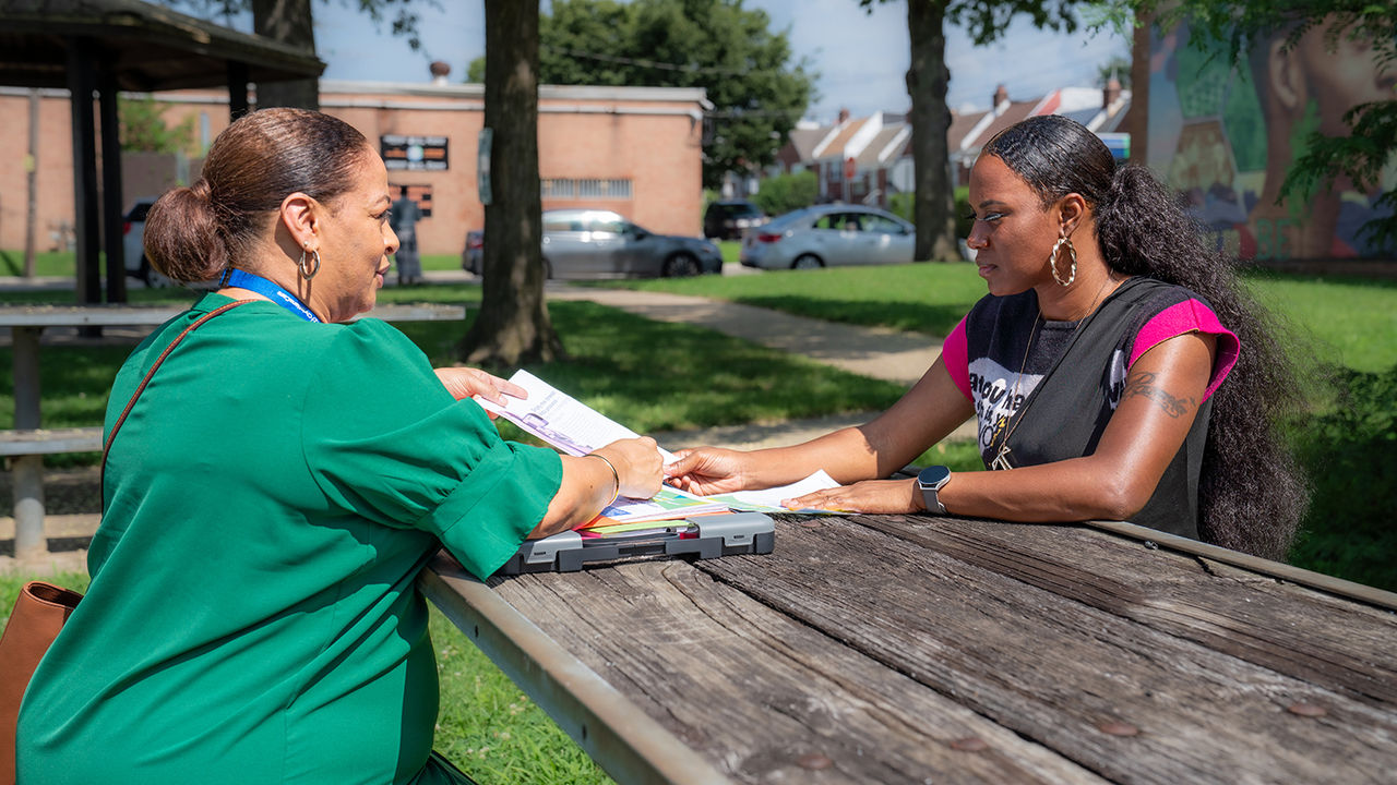 A ChristianaCare community health worker speaks with a patient at a picnic table