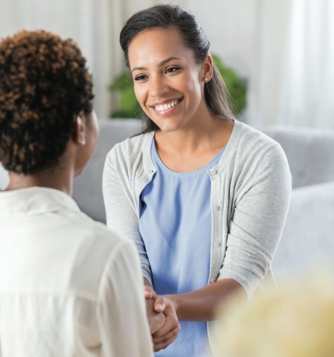 Carer smiling and holding hands with patient