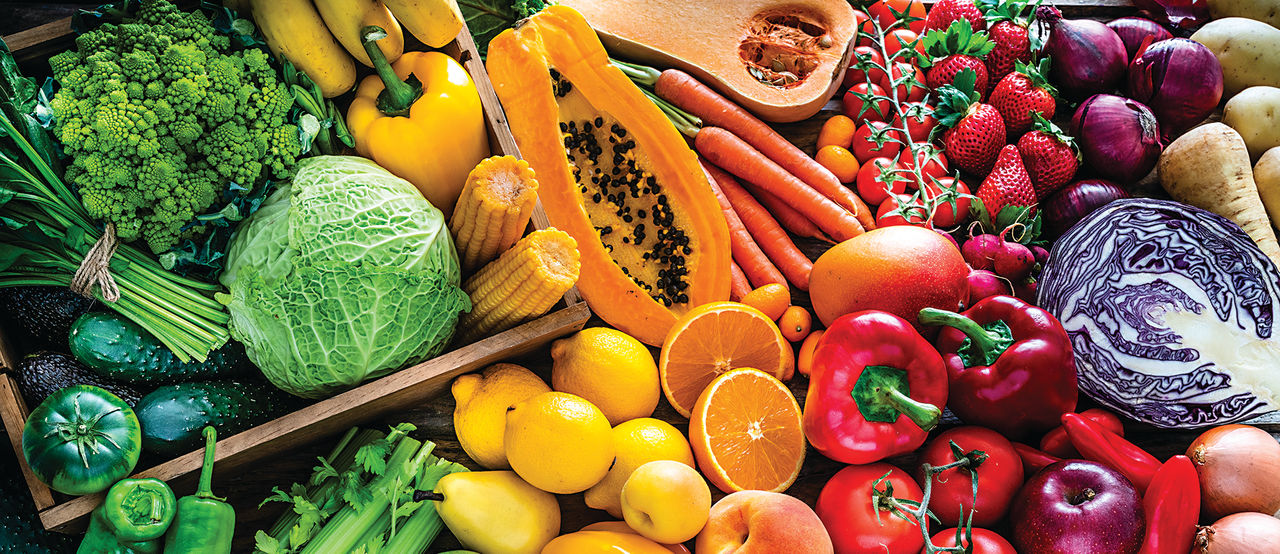 High angle view of a large assortment of healthy fresh rainbow colored organic fruits and vegetables. The composition includes cabbage, carrots, onion, tomatoes, raw potato, avocado, asparagus, eggplant, celery, cucumber, broccoli, squash, lettuce, spinac