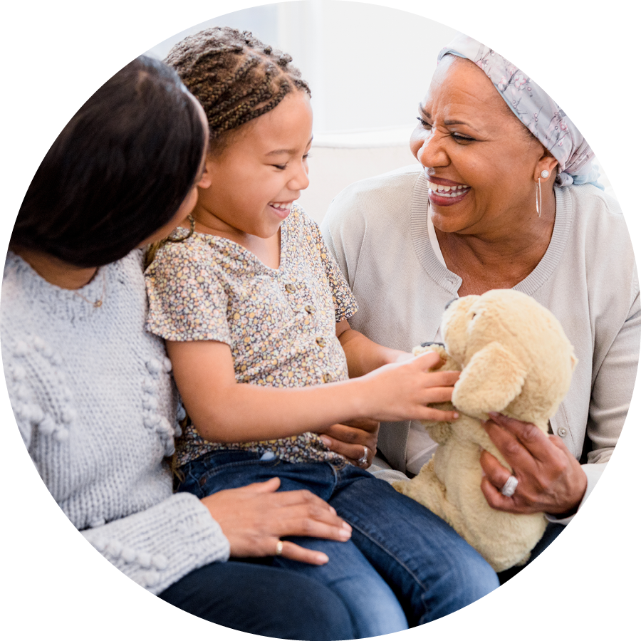 A cancer survivor plays with a stuffed animal with her daughter and granddaughter