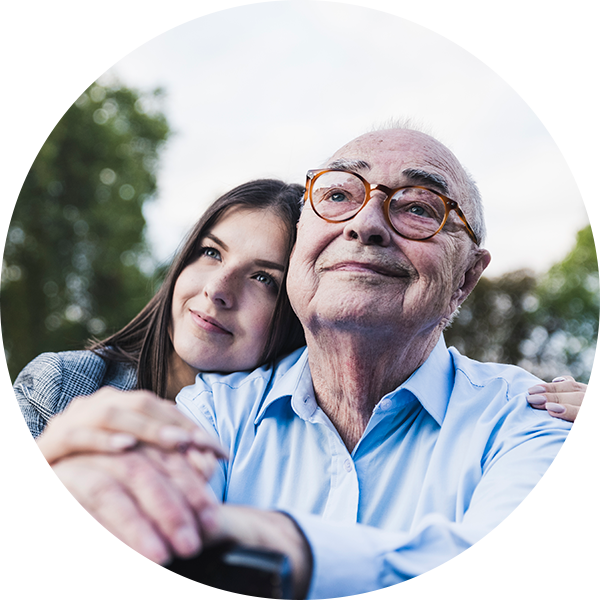 A young woman hugs her grandfather as they look off into the distance