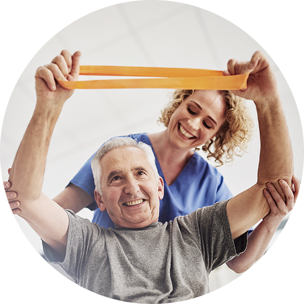 A physical therapist assists an older man with a stretching and strengthening exercise.