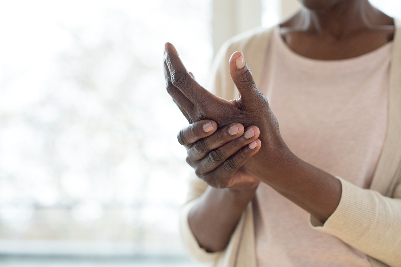 A woman massages her hands to relieve pain