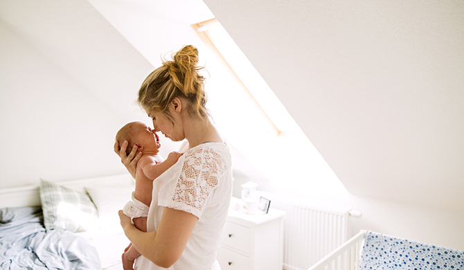Mother holding baby in bedroom