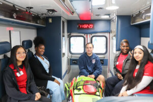 Students and a ChristianaCare crew member sit inside an ambulance during a hands-on exploration at William Penn Career Day.