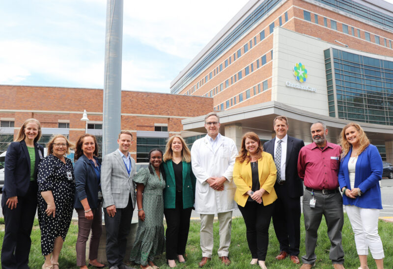 At the flag raising event, ChristianaCare caregivers and members of the Gift of Life team joined transplant recipient Onyi Kenine (in green dress) who received a donor liver as a child.
