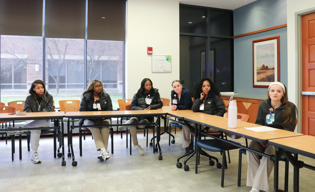 Mobility interns sit together at a table during a group discussion or meeting.
