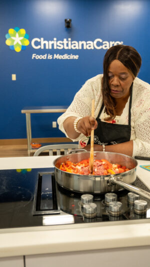 Arlene Daniels stirring a large pot on a cooker