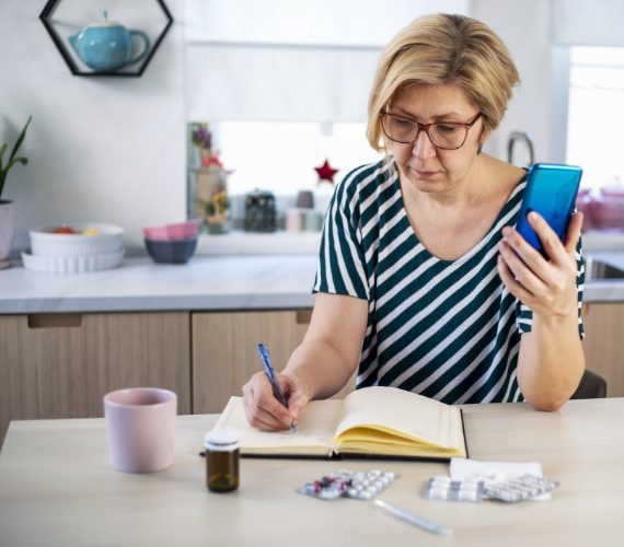 Woman on the phone with medication and notebook