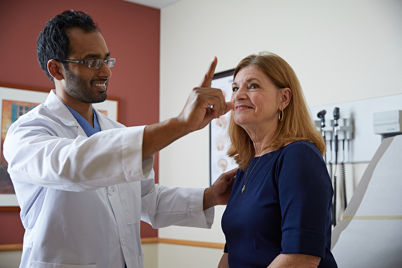 Un médico que orienta a una víctima de un accidente cerebrovascular a través de la terapia y la evaluación.
